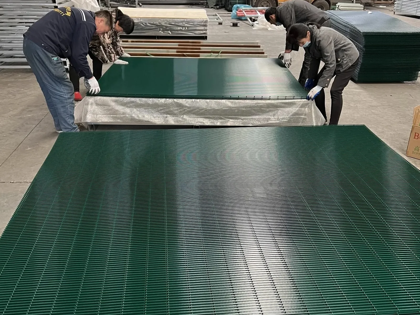 Green welded mesh fence panels being organized after production